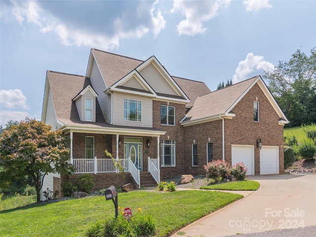 view of front of house featuring a front yard, concrete driveway, brick siding, a garage, and a porch