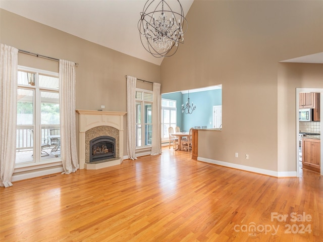 unfurnished living room with a wealth of natural light, a notable chandelier, and light hardwood / wood-style flooring