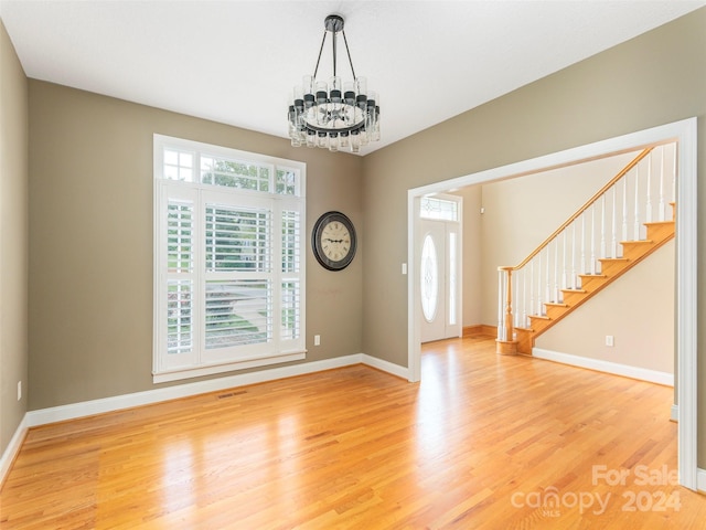 entryway with baseboards, light wood-style flooring, stairway, and a chandelier