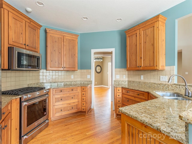 kitchen with light hardwood / wood-style flooring, sink, light stone countertops, decorative backsplash, and appliances with stainless steel finishes