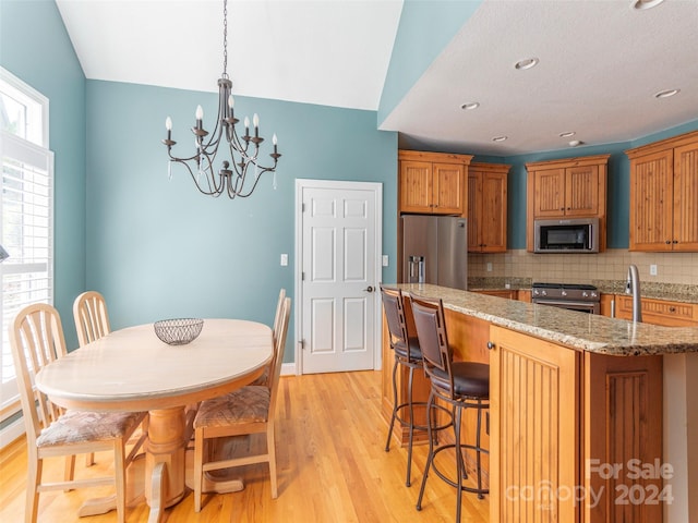 dining space with vaulted ceiling, light hardwood / wood-style flooring, a chandelier, and sink