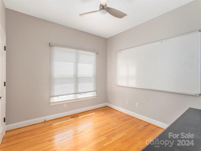 empty room with wood finished floors, baseboards, and ceiling fan
