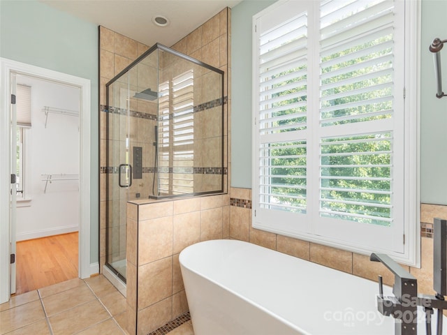 bathroom featuring tile patterned flooring, a healthy amount of sunlight, and separate shower and tub