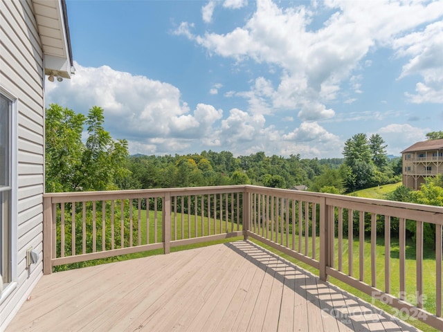 wooden terrace with a lawn and a wooded view