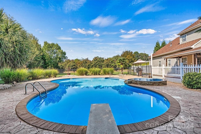 view of swimming pool with a diving board, a patio area, and an in ground hot tub