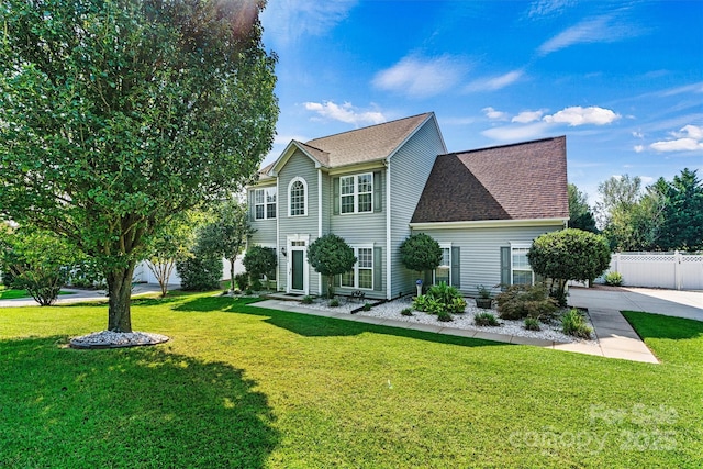 view of front facade featuring a shingled roof, fence, and a front yard