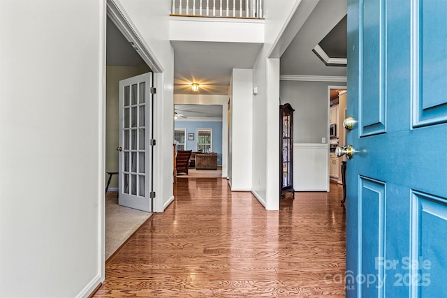 entrance foyer with ornamental molding, wainscoting, and wood finished floors