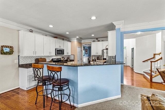 kitchen with stainless steel appliances, wood finished floors, and white cabinetry