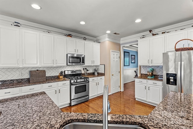 kitchen with light wood-style flooring, a sink, white cabinets, appliances with stainless steel finishes, and crown molding