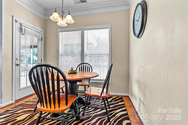 dining area with visible vents, baseboards, wood finished floors, an inviting chandelier, and crown molding