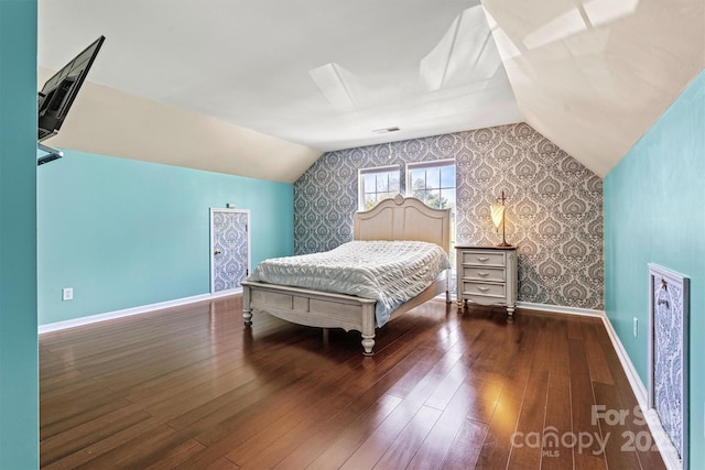 bedroom featuring visible vents, baseboards, vaulted ceiling, hardwood / wood-style floors, and wallpapered walls