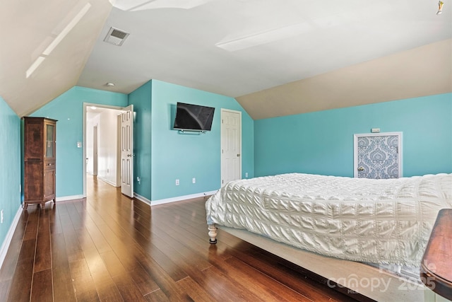 bedroom with vaulted ceiling, wood finished floors, visible vents, and baseboards