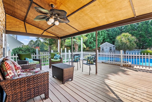 wooden terrace featuring a ceiling fan, a fenced in pool, an outbuilding, fence, and outdoor lounge area