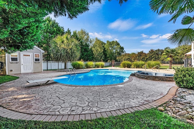 view of pool with a patio area, a pool with connected hot tub, fence, and a diving board