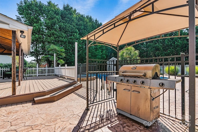 view of patio featuring a deck, fence, grilling area, and a gazebo