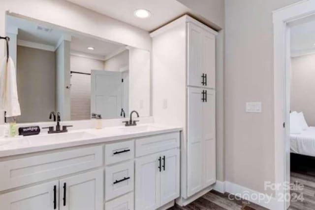 bathroom featuring hardwood / wood-style floors, crown molding, and vanity