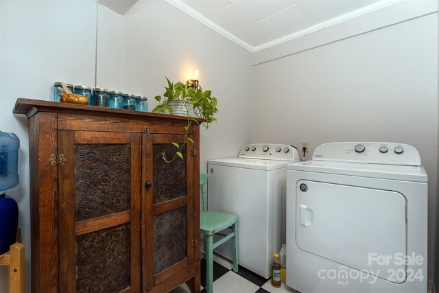 clothes washing area featuring independent washer and dryer, light tile patterned flooring, ornamental molding, and cabinets