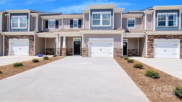 view of property featuring stone siding, concrete driveway, and a garage