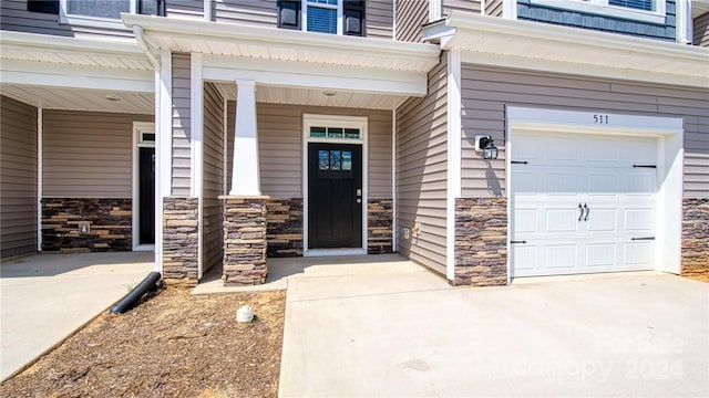 entrance to property with stone siding, driveway, and an attached garage