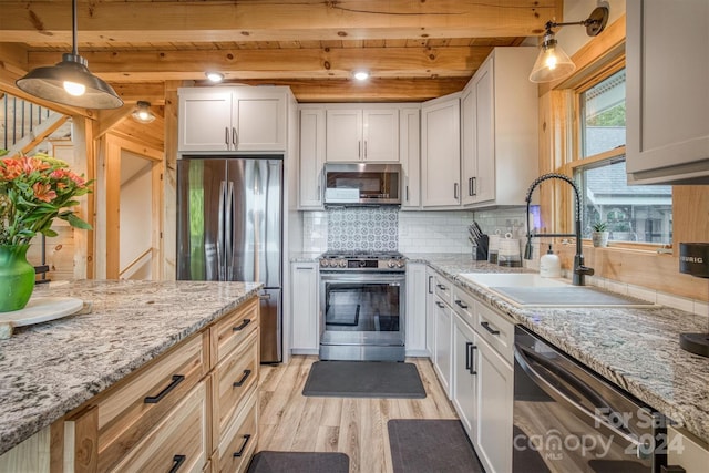 kitchen featuring backsplash, appliances with stainless steel finishes, light hardwood / wood-style floors, hanging light fixtures, and white cabinets