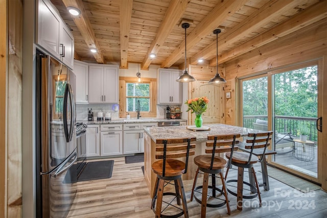 kitchen with a wealth of natural light, a kitchen island, light hardwood / wood-style flooring, and appliances with stainless steel finishes