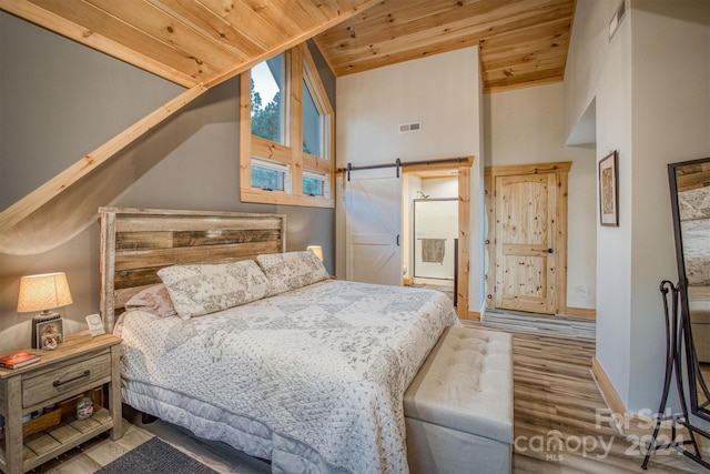 bedroom featuring wooden ceiling, high vaulted ceiling, hardwood / wood-style floors, and a barn door