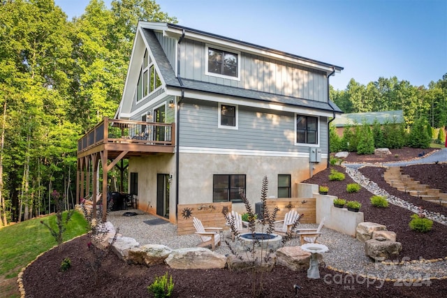 rear view of house featuring a wooden deck, a patio area, and an outdoor fire pit