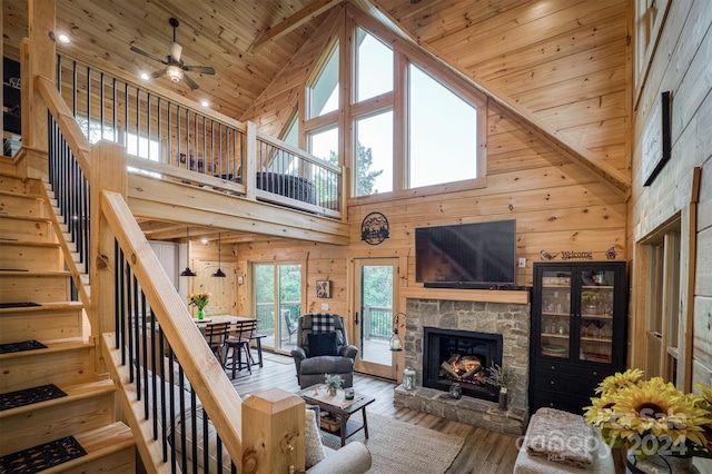 living room with a stone fireplace, wood ceiling, high vaulted ceiling, hardwood / wood-style flooring, and wooden walls