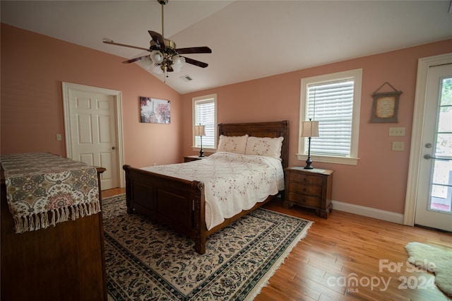 bedroom featuring light wood-type flooring, vaulted ceiling, multiple windows, and ceiling fan