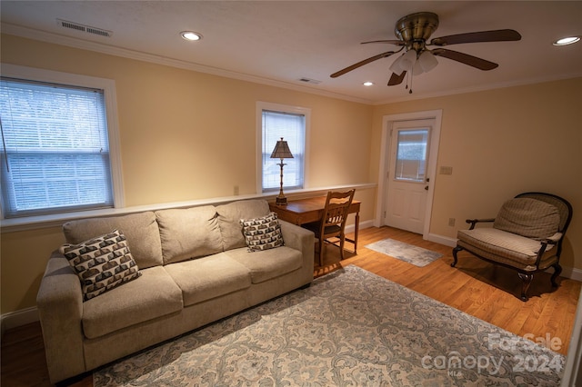 living room with ceiling fan, plenty of natural light, wood-type flooring, and ornamental molding