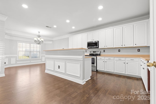 kitchen featuring appliances with stainless steel finishes, ornamental molding, white cabinetry, and pendant lighting