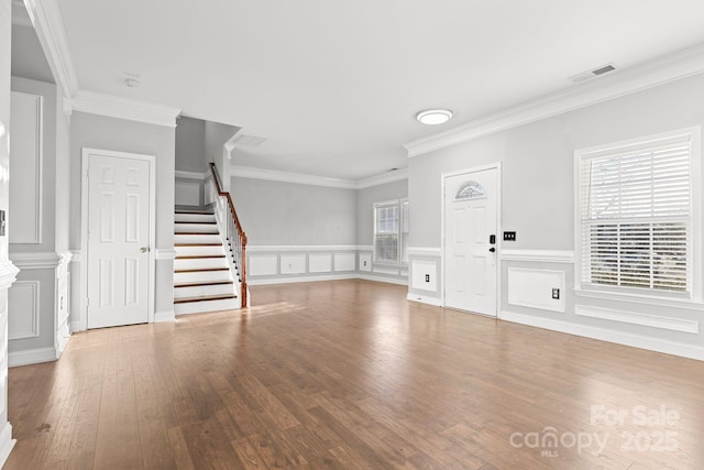 unfurnished living room featuring hardwood / wood-style flooring, a wealth of natural light, and ornamental molding