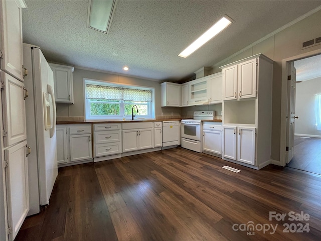 kitchen featuring visible vents, white appliances, dark wood finished floors, and vaulted ceiling