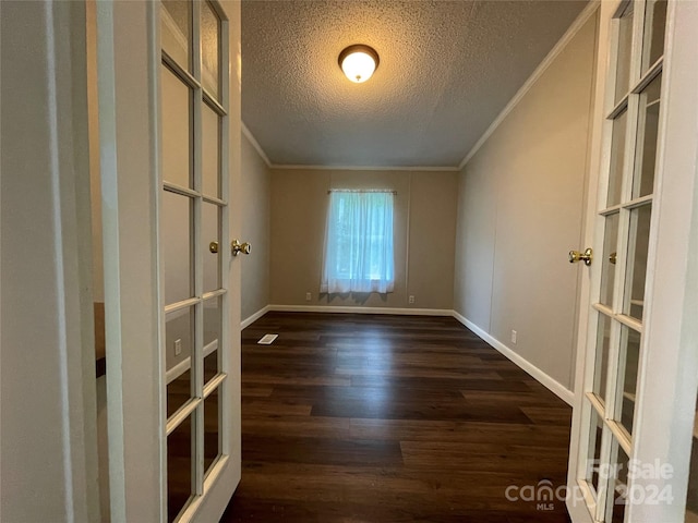 empty room with baseboards, a textured ceiling, dark wood-style flooring, and crown molding