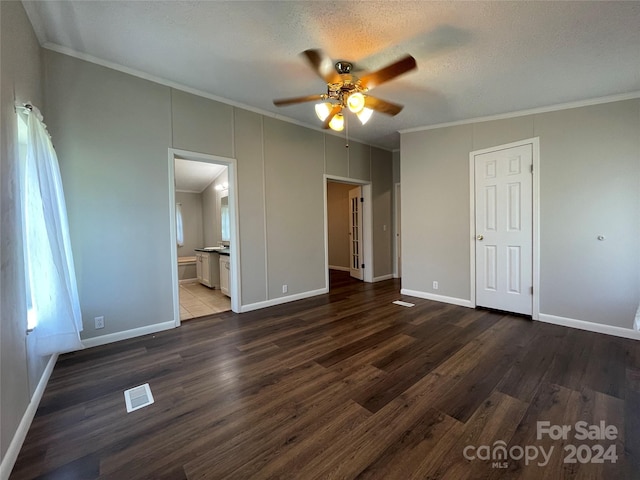 unfurnished bedroom featuring visible vents, a textured ceiling, dark wood finished floors, crown molding, and baseboards