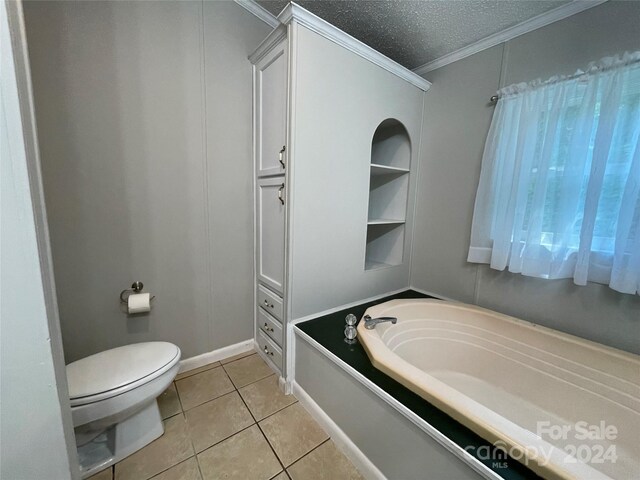 bathroom featuring tile patterned floors, a garden tub, toilet, a textured ceiling, and crown molding