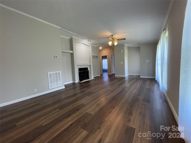 unfurnished living room with visible vents, dark wood-type flooring, a tiled fireplace, a ceiling fan, and a textured ceiling