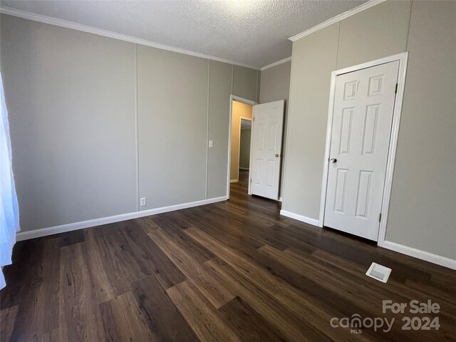 unfurnished bedroom with visible vents, crown molding, dark wood-type flooring, baseboards, and a textured ceiling