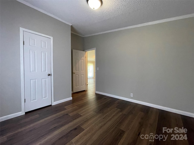 unfurnished bedroom with dark wood finished floors, a textured ceiling, baseboards, and ornamental molding