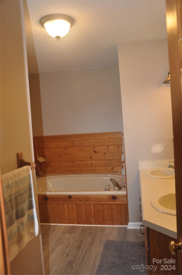 bathroom featuring hardwood / wood-style flooring, a bathing tub, and a textured ceiling