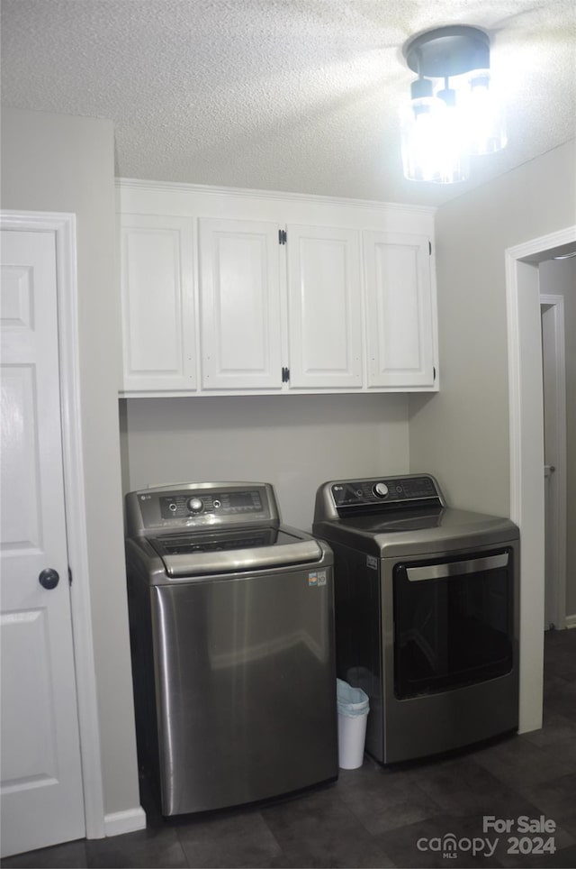 washroom with washing machine and clothes dryer, cabinets, and a textured ceiling