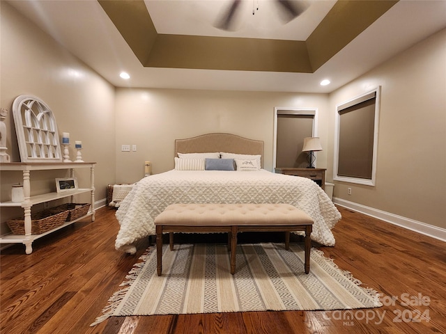 bedroom with dark hardwood / wood-style floors, a raised ceiling, and ceiling fan