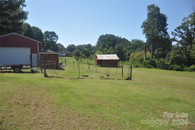 view of yard with a rural view, an outbuilding, and a garage