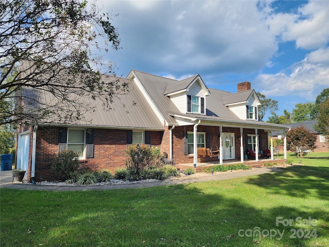 cape cod-style house featuring a garage, a porch, and a front yard