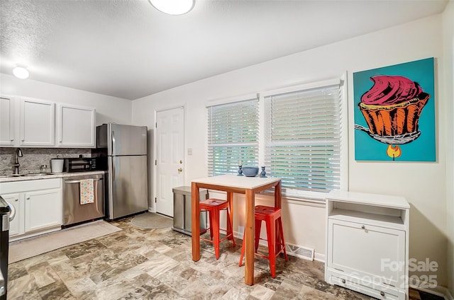 kitchen with tasteful backsplash, sink, stainless steel appliances, a textured ceiling, and white cabinets