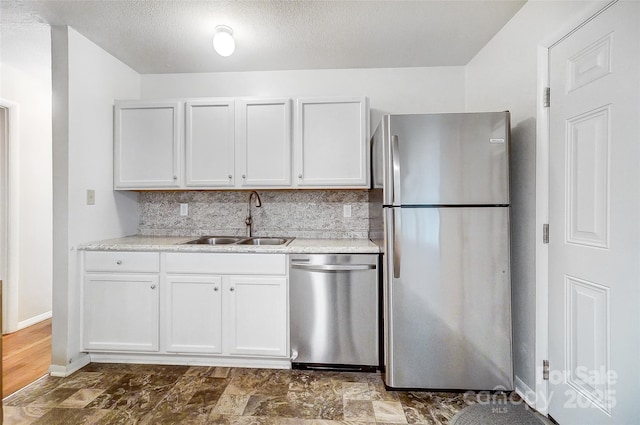 kitchen with appliances with stainless steel finishes, backsplash, a textured ceiling, white cabinets, and sink