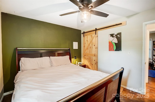 bedroom with ceiling fan, hardwood / wood-style floors, and a barn door