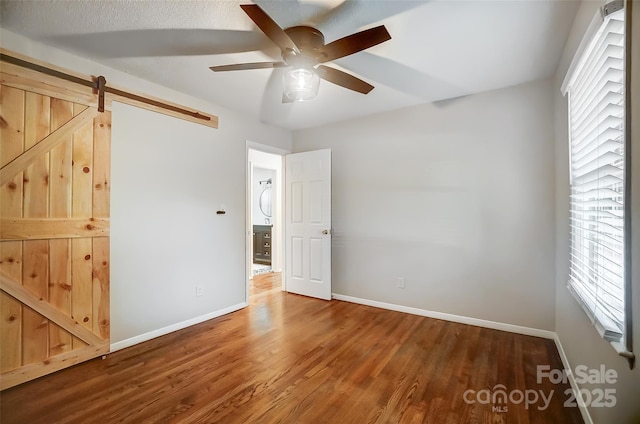 interior space featuring ceiling fan, a barn door, and hardwood / wood-style flooring