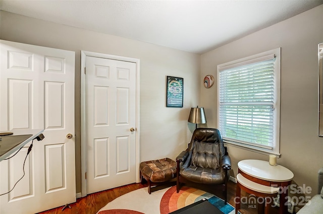 sitting room with dark wood-type flooring and a healthy amount of sunlight