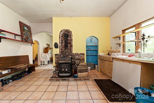 interior space with arched walkways, light tile patterned floors, and a wood stove